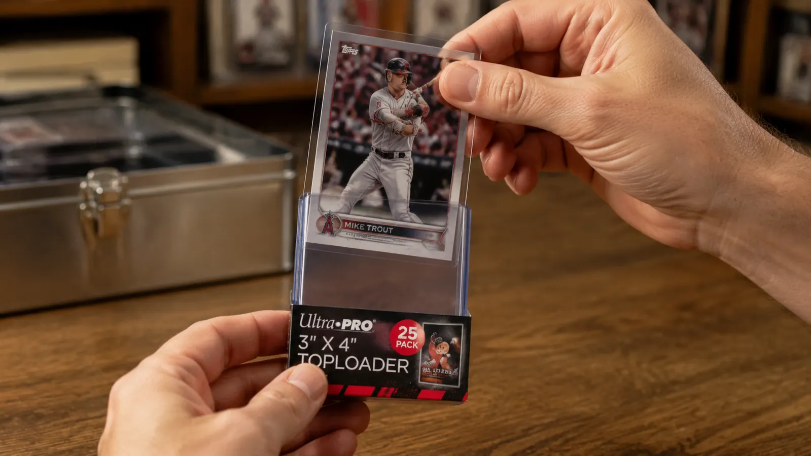 Hand sliding a sleeved baseball card into an Ultra Pro top loader from above